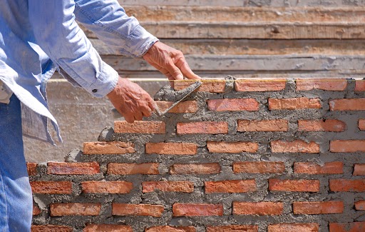 a person using a trowel to lay a brick wall