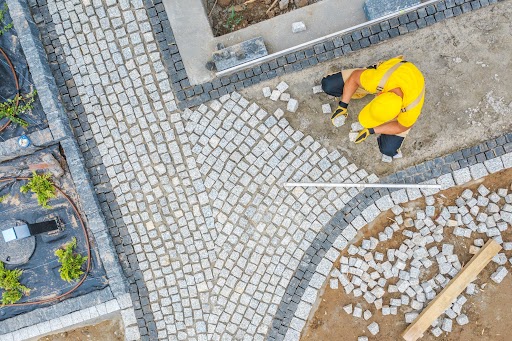 Caucasian Construction Worker in His 40s Paving Garden Path Aerial View. Garden Architecture Theme.