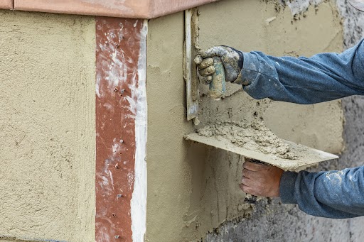 a person using a trowel to put cement on a wall