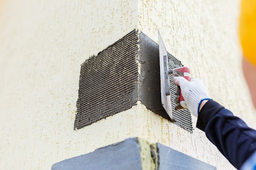 a person using a trowel to put a cement on a wall